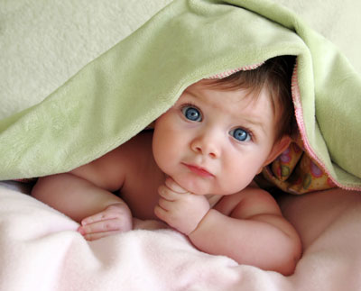 a baby playing under a green blanket